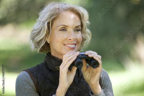 Photo: A mature woman outdoors, holding a pair of binoculars A mature woman outdoors, holding a pair of binoculars