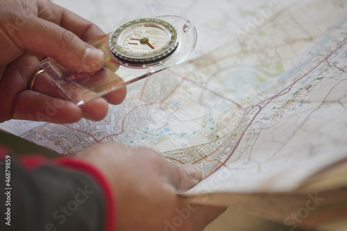 Photo: A man holding a map and compass, close up A man holding a map and compass, close up