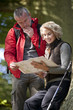 A mature couple standing in woodland looking at a map, close up