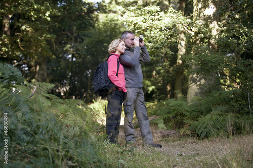 Photo: A mature couple looking through binoculars in the countryside A mature couple looking through binoculars in the countryside