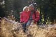 A mature couple sitting on a tree trunk embracing
