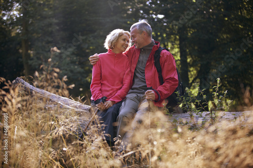 Photo: A mature couple sitting on a tree trunk embracing A mature couple sitting on a tree trunk embracing