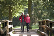 A mature couple walking over a footbridge in the countryside