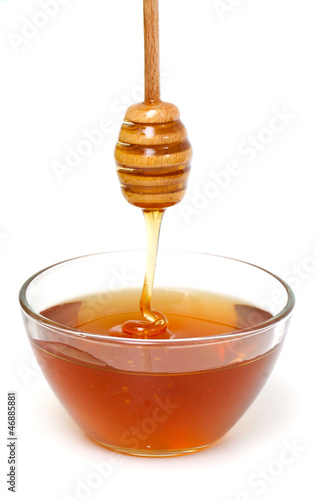 Photo: Honey dripping from a wooden honey dipper on white background Honey dripping from a wooden honey dipper on white background