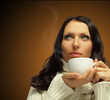 Photo: Woman with hot coffee on dark brown background Woman with hot coffee on dark brown background