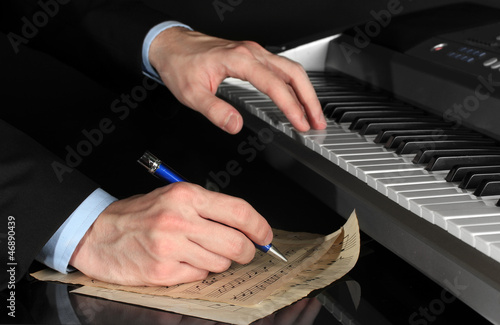 Photo: man hands playing piano and writes on parer for notes man hands playing piano and writes on parer for notes