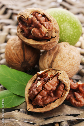 Photo: walnuts with green leaves, on wicker background walnuts with green leaves, on wicker background