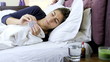 Sick woman in bed taking aspirin