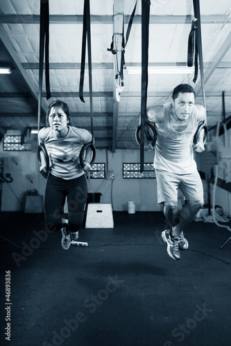 Photo: Young gymnasts training on rings on a dark background Young gymnasts training on rings on a dark background