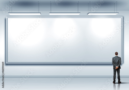 Photo: Business person standing near a blank billboard Business person standing near a blank billboard