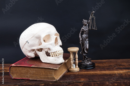 Photo: old book human scull and temida statue old book human scull and temida statue