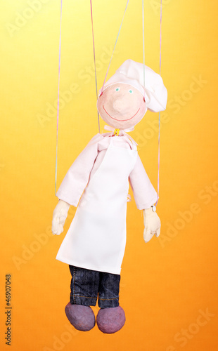 Photo: Wooden puppet as cook on orange background Wooden puppet as cook on orange background