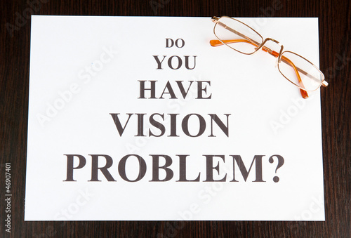 Photo: Eyesight test chart with glasses on wooden background close-up Eyesight test chart with glasses on wooden background close-up