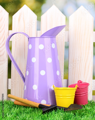 Photo: gardening tools on green grass on wooden fence background gardening tools on green grass on wooden fence background