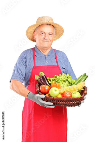 Photo: Mature farmer man holding a basket with fresh vegetables Mature farmer man holding a basket with fresh vegetables