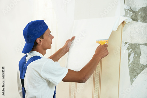 Photo: painter worker peeling off wallpaper painter worker peeling off wallpaper