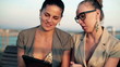 Two ladies with tablet computer sitting on bench, steadycam shot