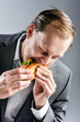Man in suit eats BLT eagerly hungrily