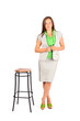 Young beautiful business woman stands near tall stool in studio