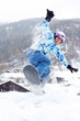 Smiling snowboarder jumps on snowboard on mountain