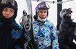 Three skiers in helmets ride on funicular in mountains.
