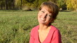 A young woman in a red sweater smiling sitting in autumn park