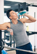 Young asian man having a rest drinking a beverage in the gym.