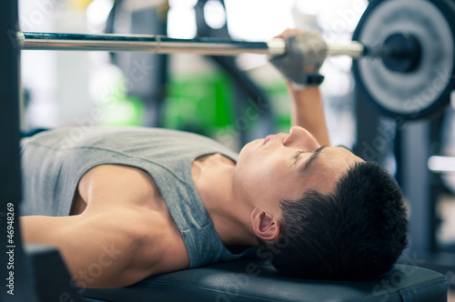 Photo: Young man lifting the barbell in the gym. Young man lifting the barbell in the gym.