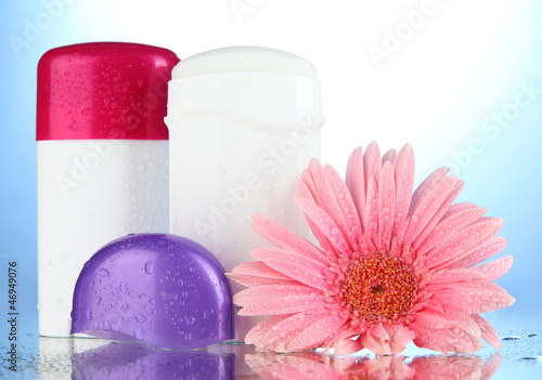 Photo: deodorant botttles with flower on blue background deodorant botttles with flower on blue background
