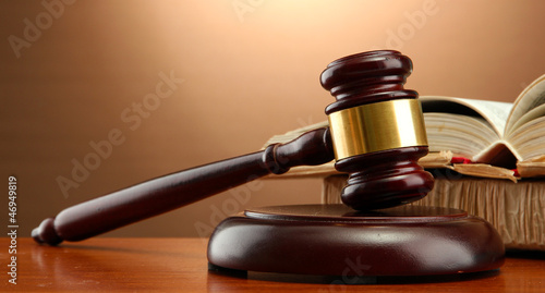 Photo: wooden gavel and books on wooden table,on brown background wooden gavel and books on wooden table,on brown background