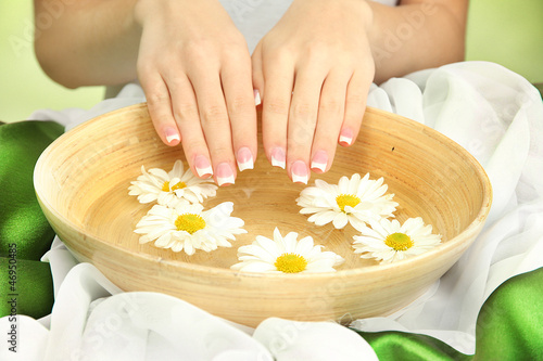 Photo: woman hands with wooden bowl of water with flowers, woman hands with wooden bowl of water with flowers,