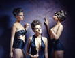 Three young women of model pose against a dark background