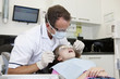 A male dentist examining a young girls teeth