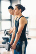 Two young men exercising with dumbbells in the gym.