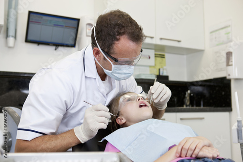 Photo: A male dentist examining a young girls teeth A male dentist examining a young girls teeth