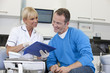 A female dentist discussing dental records with her male patient