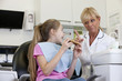 A young girl at the dentist eating a giant cookie