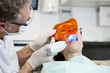 Foto: A male dentist filling a female patients teeth A male dentist filling a female patients teeth