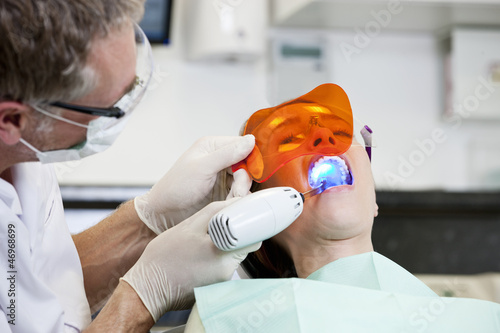Photo: A male dentist filling a female patients teeth A male dentist filling a female patients teeth