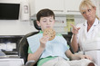 A young boy at the dentist holding a giant cookie