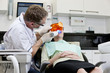 Photo: A male dentist filling a female patients teeth A male dentist filling a female patients teeth