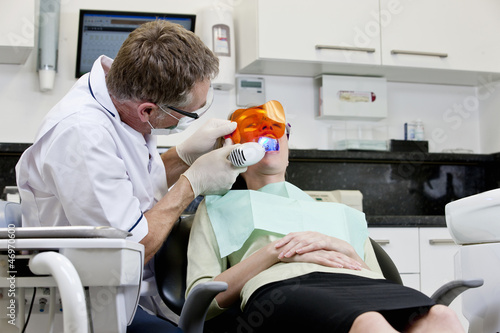 Photo: A male dentist filling a female patients teeth A male dentist filling a female patients teeth
