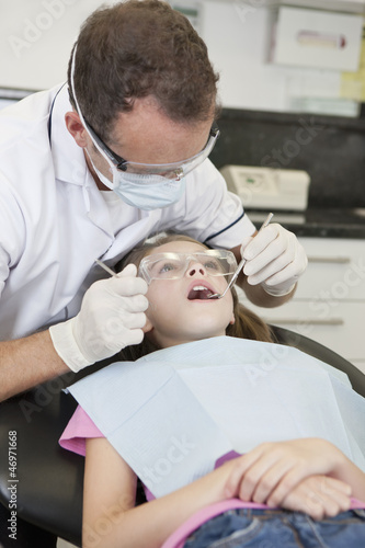 Photo: A male dentist examining a young girls teeth A male dentist examining a young girls teeth