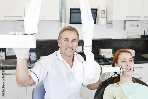 Photo: A male dentist taking an x-ray of a female patients teeth A male dentist taking an x-ray of a female patients teeth