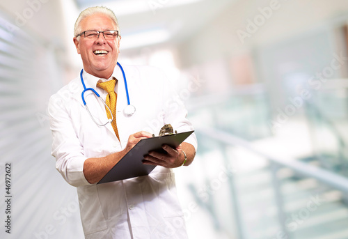 Photo: Happy Male Doctor Writing On Clipboard Happy Male Doctor Writing On Clipboard
