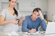 Photo: Disappointed couple in the kitchen cutting credit card Disappointed couple in the kitchen cutting credit card