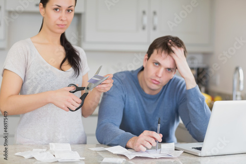 Photo: Disappointed couple in the kitchen cutting credit card Disappointed couple in the kitchen cutting credit card