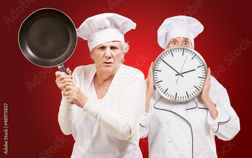 Photo: Two Female Chef Holding Saucepan And Clock Two Female Chef Holding Saucepan And Clock