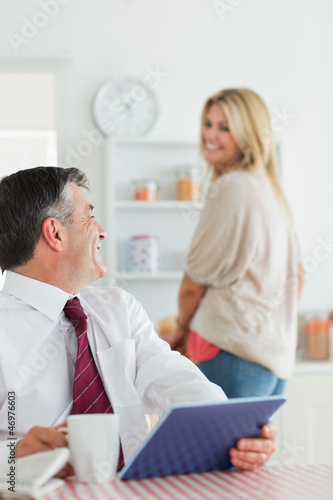 Photo: Couple smiling at each other at the kitchen before work Couple smiling at each other at the kitchen before work