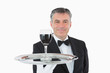 Smiling waiter holding a glass of wine on a silver tray